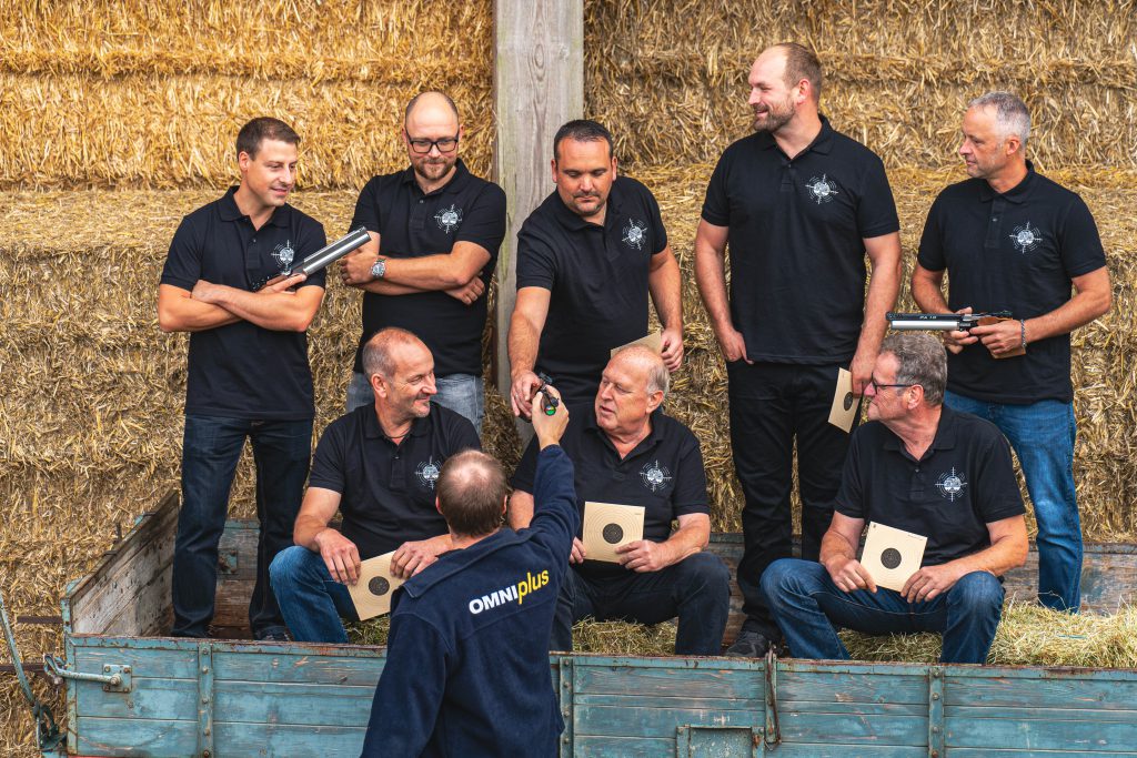 Eine Gruppe Männer steht auf einen Traktoranhänger und bereitet sich auf Fotoaufnahmen vor.