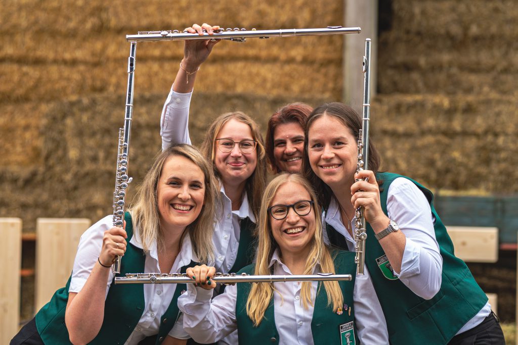 Fünf Frauen stehen für ein Gruppenbild zusammen. Sie haben ihre Querflöten zum Rahmen arrangiert