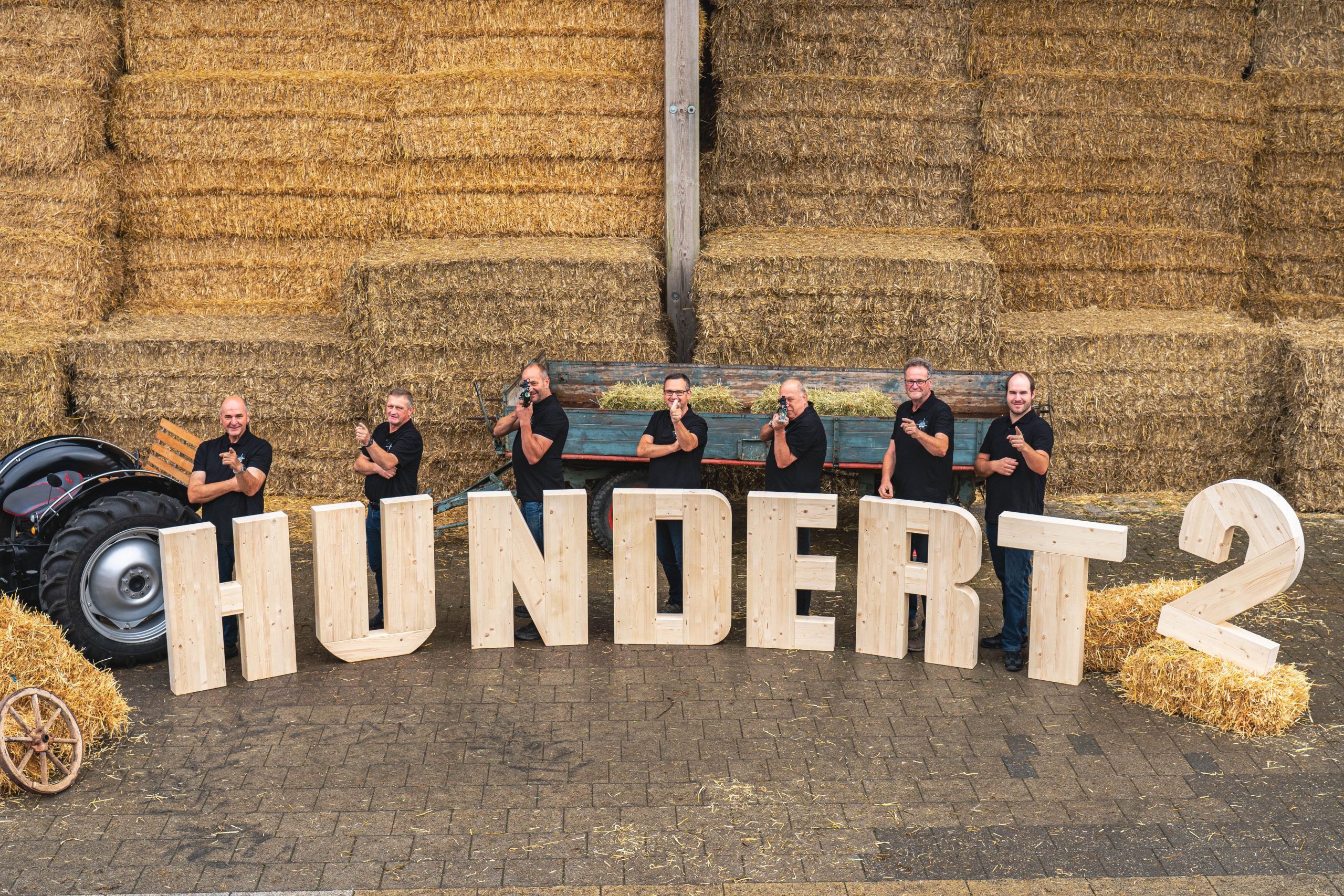 Eine Gruppe Männer steht zu einem Gruppenbild zusammen. Sie zielen mit ihren Sportgewehren und Fingern auf die Kamera